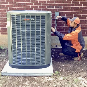 Outdoor HVAC condenser units beside a brick wall.