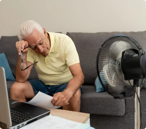 Man sitting on couch with fan blowing on him