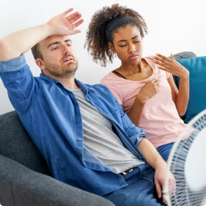 Couple on the couch with fan in heat