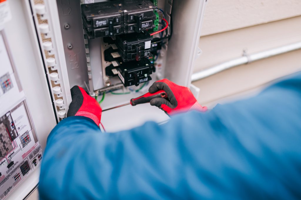 A technician checking the electrical panel on a house